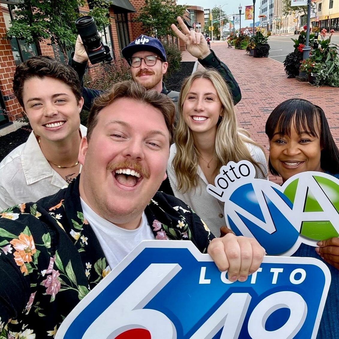 Jared Goodman with the Atlantic Lottery social and creative team on Main Street, Moncton β holding Lotto 6/49 and Lotto MAX cutouts